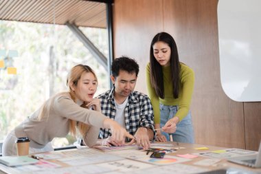 Modern bir ofiste yaratıcı bir proje üzerinde birlikte çalışan çeşitli meslektaşlar beyin fırtınası ve tartışmalar yapıyorlar..