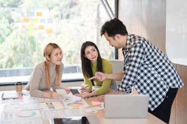 Çağdaş ofis alanındaki bir masada materyalleri incelerken tasarım kavramları hakkında canlı bir tartışmaya giren çeşitli bir takım..