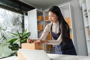 Profesyonel bir kadın, envanterini modern bir ofiste yönetirken paketleri etiketler. Organizasyon becerilerini ve adanmışlığını yansıtır..