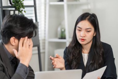 Odaklanmış bir kadın profesyonel, işyeri dinamiklerini ön plana çıkaran, gözle görülür derecede stresli bir erkek meslektaşla proje konularını ele alıyor.