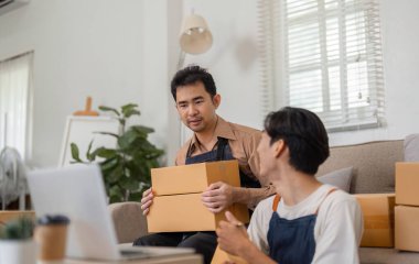 İki çok kültürlü girişimci, evlerindeki çevrimiçi mağazaları için kutu paketlerken nakliye lojistiği hakkında canlı bir tartışmaya giriştiler..