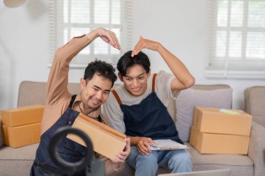 Çevrelerinde paketler ve şık oturma odalarında bir dizüstü bilgisayar varken iki hevesli online satıcı fikir üretiyor..