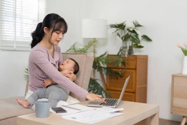 Kendini işine adamış bir anne bir eliyle dizüstü bilgisayarını kullanırken diğer eliyle bebeğini kucağına alıp şık bir ofis ortamında yaşıyor..