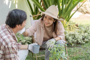 Yaşlı bir Asyalı çift bahçelerinde neşe dolu bir anı paylaşıyor. Kadın, partnerinin yüzüne şefkatle dokunuyor ve gülümsüyor..