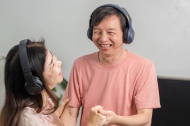 Evde kulaklık takmış, gülüp dans eden olgun bir çift birlikte vakit geçiriyorlar ve neşeli bir atmosferde müzik dinliyorlar..