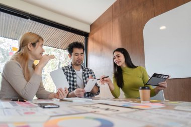 Çağdaş bir çalışma alanında tasarım kavramları üzerine tartışma ve geri bildirim yapan çeşitli bir tasarım ekibi.