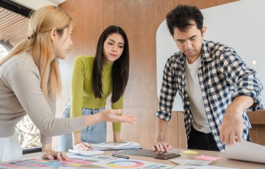 Çeşitli yaratıcı profesyonellerden oluşan bir grup fikirleri tartışıyor ve modern ofis çalışma alanında bir tasarım projesi üzerinde birlikte çalışıyorlar..