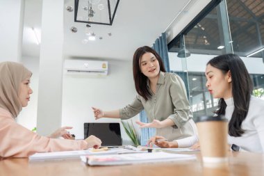Finansal profesyonellerden oluşan çeşitli bir ekip çağdaş bir ofis ortamında strateji ve raporlar üzerinde işbirliği yapmaktadır..