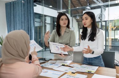 Profesyoneller bilgilerini paylaşıyor ve enerjik bir ofis ortamında mali stratejileri tartışıyor, takım çalışmasını ve işbirliğini vurguluyor.