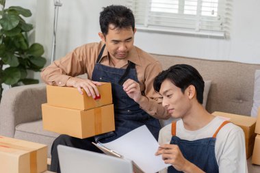 Two online entrepreneurs discuss package details while preparing for shipment, highlighting their teamwork and business acumen. clipart