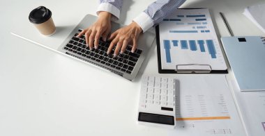 İki finans uzmanı birlikte çalışıyor, vergi raporlarını ve grafiklerini analiz ediyor, muhasebe alanında takım çalışması sergiliyor.