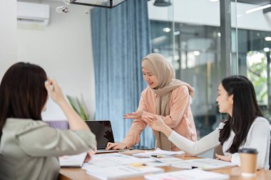 Bir grup kadın aktif olarak bir toplantıya katılıyor, işbirlikçi bir ortamda görüşlerini ve stratejilerini paylaşıyor.