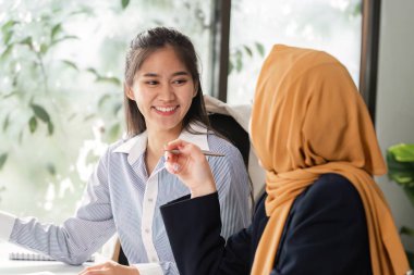 Çeşitli kadın grupları bir ofis ortamında iş birliği yaparak finansal stratejileri tartışıyor ve görüşlerini paylaşıyorlar..