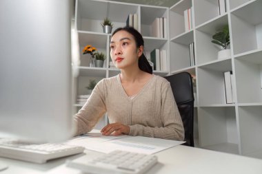 Adanmış bir ofis çalışanı finansal raporları ve verileri gözden geçirir, konsantrasyon ve profesyonelliği çağdaş bir ortamda gösterir.