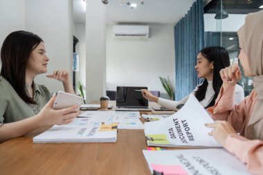 Kadınların mali raporları ve stratejileri tartıştığı, takım çalışması ve işbirliği sergilediği bir ofiste profesyonel bir toplantı..