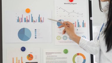 Bir el, bir iş sunumundaki içgörü ve eğilimleri vurgulayarak, bir tablodaki mali grafiklere ve verilere işaret eder..