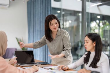 Bir grup profesyonel kadın, bütçe ve mali stratejileri çizelgeler ve belgelerle tartışan bir toplantıda işbirliği yapıyor..