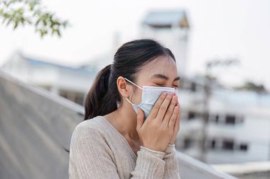 Dışarıdayken maskesini takan bir kadın, kirli ortamlarda sağlık bilincinin önemini vurguluyor..