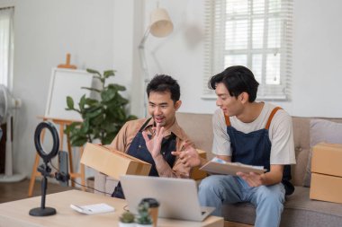 İki neşeli çevrimiçi satıcı sıcak ofislerinde paketler ve bir dizüstü bilgisayarla uğraşırken canlı bir tartışma içindeler..