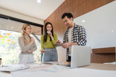 Proje fikirlerini tartışan çeşitli profesyonellerden oluşan bir grup, modern ofis çalışma alanlarında yaratıcı süreçlerini geliştirmek için dijital tablet kullanıyor..