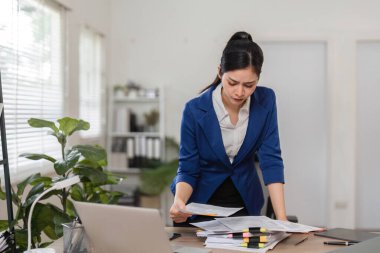 Bir muhasebeci, iyi organize edilmiş bir ofis ortamında doğru vergi dosyalarını dikkatlice analiz eder..