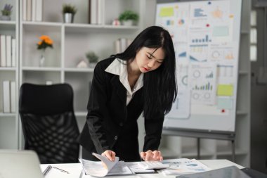 Bir muhasebeci, modern ofis ortamında mali belgeleri ve raporları titizlikle inceler..