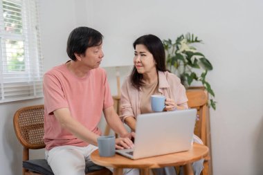 Yaşlı bir çift online aktiviteler hakkında ciddi bir tartışmaya girişiyor, rahat çalışma alanlarında birlikte kahve yudumluyorlar..