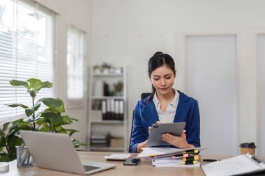 Bir muhasebeci, organize çalışma alanındaki modern teknolojiyi gösteren bir tabletin mali raporlarını inceliyor..