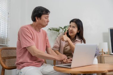 Üst düzey bir çift, rahat bir ev ortamında sevgi ve neşe göstererek dizüstü bilgisayar kullanırken eğlenceli bir etkileşimden zevk alıyor..