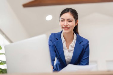 Profesyonel bir iş kadını, işine olan bağlılığını göstermek için finansal belgeleri dizüstü bilgisayarında gözden geçirir..