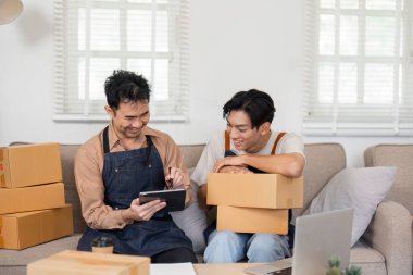 İki adam internetteki iş performanslarını heyecan içinde analiz ediyor. Etrafı kutularla çevrili..