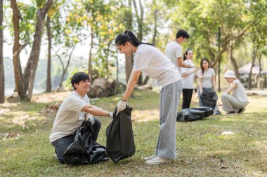 Gönüllüler parktaki çöpleri aktif olarak topluyorlar, toplumsal katılım yoluyla sürdürülebilirliği ve çevresel farkındalığı destekliyorlar..