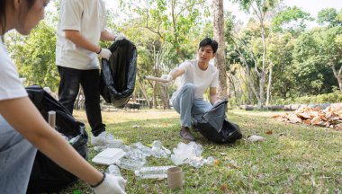 Gönüllüler bir park temizliği sırasında çöpleri ayırıyor, takım çalışması ve çevre sorumluluğunu vurguluyorlar.