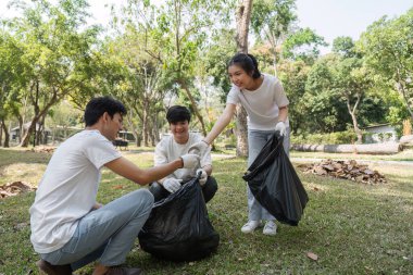 Bir grup gönüllü, atık toplarken dostça sohbete girişerek, sürdürülebilirliğe toplumsal katılımın önemini vurguluyor.