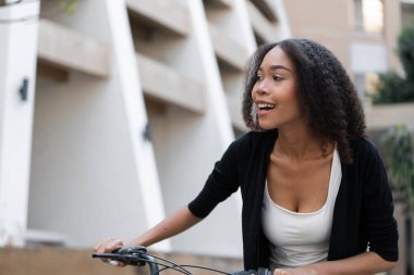 Kentsel bir alanda yakalanan bir kadın, neşeli ve çevreci bir yaklaşım sergileyen bisikletine coşkuyla biniyor..