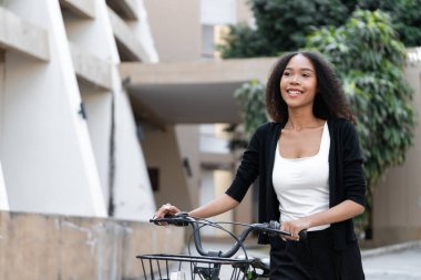 Kendine güvenen bir kadın bisikletiyle modern bir şehir ortamında dolaşarak sürdürülebilirlik ve sağlıklı yaşama bağlılığını gösteriyor..