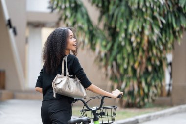 Bir bisikletçi, canlı bir şehirde, çevre dostu yaşamın güzelliğini yansıtarak çevresini takdir etmek için durur. Bisikleti sürdürülebilir ulaşımı sembolize ediyor..