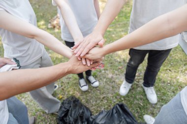 Gönüllüler, temizlik projesi ve kamu hizmetine olan bağlılıklarını vurgulayarak bir dayanışma jesti olarak ellerini birleştiriyorlar..