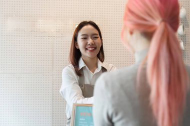 Sıcak bir kafe ortamında, bir barista sıcak bir gülümseme ile müşteriyi karşılar, dostça hizmet ve bağlantı yoluyla kahve deneyimini artırır..