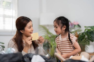 Sıcacık bir ortamda, bir anne geri dönüşümlü bir nesneyi elinde tutuyor, kızını gezegene faydası olan sürdürülebilir uygulamalar hakkında bir tartışmaya sokuyor..
