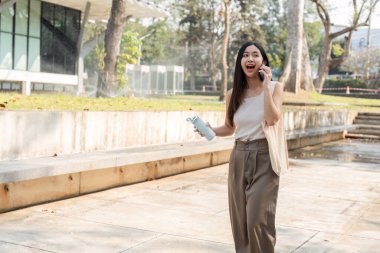 Genç bir kadın telefonda konuşurken heyecanla yürüyor, sürdürülebilir bir yaşam tarzına olan bağlılığını gösteriyor..