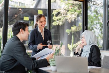 Çeşitli bir ekip, buluşmaları sırasında yenilikçi sürdürülebilirlik uygulamalarını, işbirliği göstermeyi ve çevresel sorumluluğa bağlılığı tartışır..