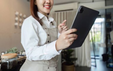 Dost canlısı bir barista tabletle ilgilenir, siparişleri yönetir ve müşterilere kusursuz bir kafe deneyimi sunar..