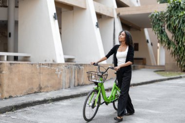 Yeşil bisikletiyle gezen bir kadın, günlük rutininde sürdürülebilir seçimler yaparken hayatın basit zevklerinden zevk alıyor..