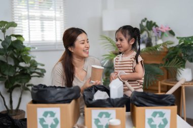 Anne kızına geri dönüşüm hakkında öğretiyor, sıradan kağıt bardakları eğlenceli bir yaratıcı projeye dönüştürüyor, sürdürülebilirliğin önemini vurguluyor..