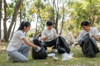Gönüllüler parktaki çöpleri toplama ve ayıklama işiyle uğraşıyorlar, çevresel bakıma olan bağlılıklarını vurguluyorlar..