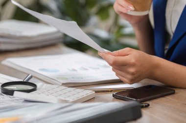 Finansal raporları yakından inceleyen bir şahıs, etkin iş planlaması ve vergi uyumu için gerekli analizleri sergiliyor.