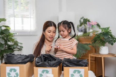 Bir anne, eğlenceli ve ilgi çekici bir aktiviteyle kızına farklı materyallerin geri dönüşümünü öğrenmesi ve sürdürülebilir alışkanlıkları güçlendirmesi için rehberlik eder..