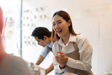 Kahveci, dostça bir gülümsemeyle müşterileri hoş karşılar, kahvecilerinde canlı ve davetkar bir atmosfere katkıda bulunur..