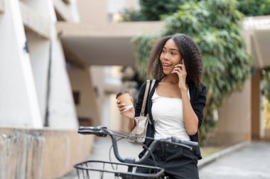 Bir kadın kahvenin tadını çıkarırken hayat dolu bir telefon görüşmesi yapar, bisikletinin üzerinde ustalıkla şehir çevresini dolaşır..